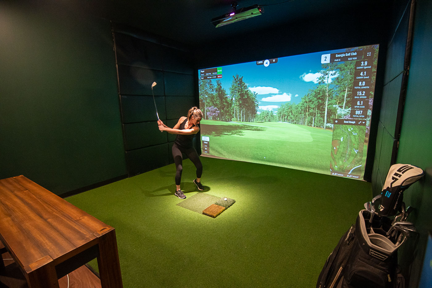 Wide Shot of Golfer Swings in Front of a Indoor Golf Simulator Screen