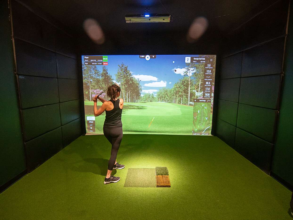Wide Shot of Golfer Swings in Front of a Indoor Golf Simulator Screen