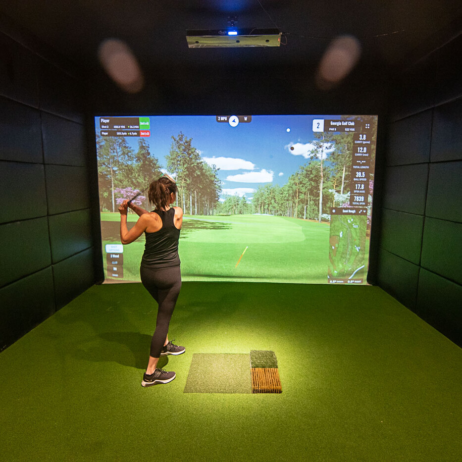 Wide Shot of Golfer Swings in Front of a Indoor Golf Simulator Screen