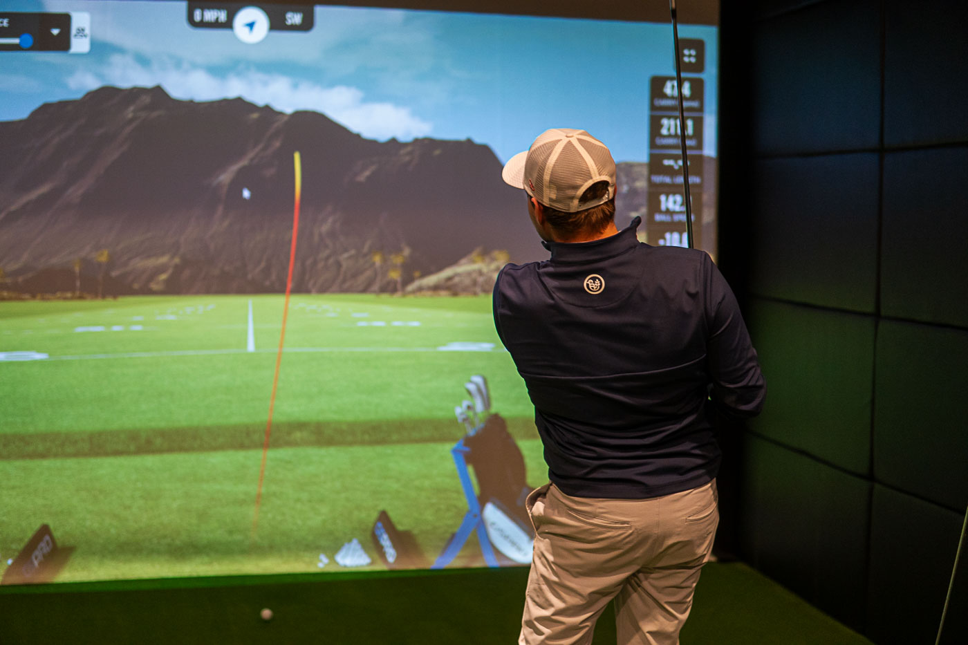 Golfer Finishes Shot in Front of a Indoor Golf Simulator Screen